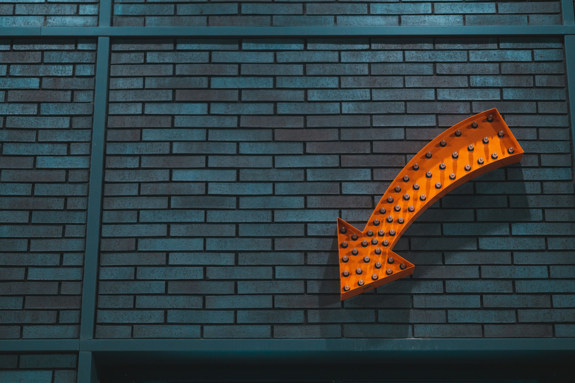 orange arrow pointing downwards against a grey wall