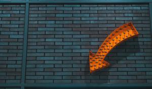 orange arrow pointing downwards against a grey wall